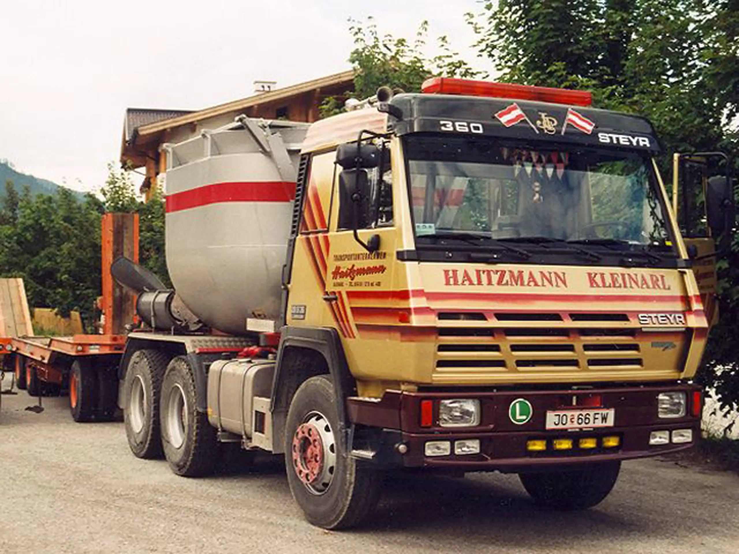 Lastwagen Steyr 360 mit Betonmischer und Anhänger vor Haus und Bäumen in Kleinarl, beschriftet mit Haitzmann Transporte